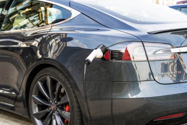 Minsk, Belarus - August 12, 2022: Tesla car charges the electric motor at the charging station on the street. Electric cars, ecology, transport concept. High quality photo