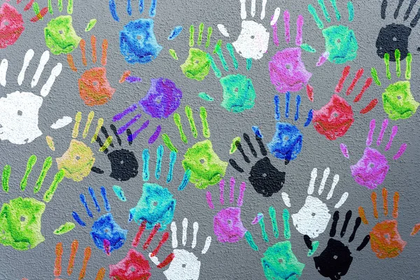 Colored hand palms on a gray wall. Childrens handprints background. Charity, joy, party, holiday concept. High quality photo