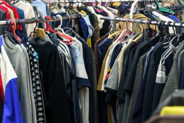 Second hand vintage clothes in a store on sale. Fashionable European used retro jeans, t-shirts, dresses, pants and accessories. Recycling and life extension for clothes concept. High quality photo