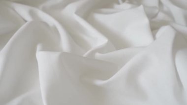 White fabric. Drapery wavy texture white linen cloth background on morning sunshine. Clean clothes concept. High quality FullHD footage