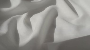 White fabric. Drapery wavy texture white linen cloth background on morning sunshine. Clean clothes concept. High quality FullHD footage