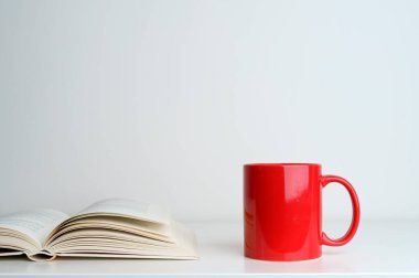 Masanın üzerinde açık bir kitap var. Beyaz sayfalı bir kitap ve boş bir arka planda bir bardak. Eğitim, okul, eğitim, okuma konsepti. Yüksek kalite fotoğraf