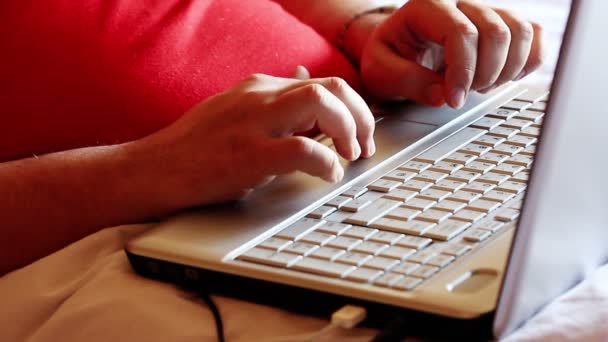 Hombre en la cama escribiendo en el ordenador portátil — Vídeos de Stock