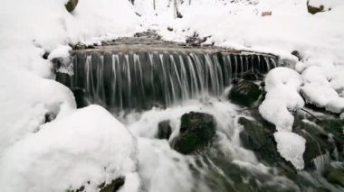 Ukrayna 'daki Karpat Dağları' nda güçlü bir su akıntısı olan harika donmuş bir şelale ayağı. Gemi. Taşlar, kayalar ormanla çevrili Noel ağaçları ve çam ağaçları