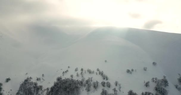 Foto aérea de majestuoso amanecer en las montañas. Valle entre las montañas está cubierto de niebla y está iluminado por los cálidos rayos del sol naciente. Montañas cubiertas de bosque natural. — Vídeos de Stock