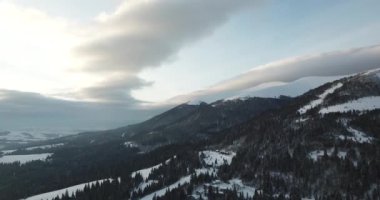 Dağlarda görkemli bir gündoğumu görüntüsü. Dağlar arasındaki vadi sisle kaplıdır ve yükselen güneşin sıcak ışınlarıyla aydınlanır. Dağlar doğal ormanlarla kaplı..