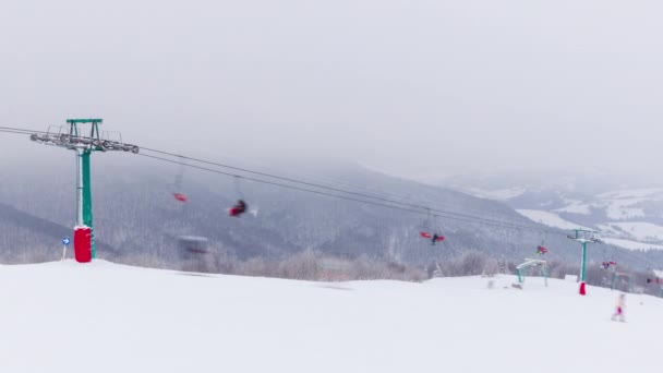 雪の背景にスキーリフト帽をかぶった山々と山の氷河。空のシングルチェアはリフトで上下に移動します。スキー、スノーボーダー、観光客が週末に訪れました — ストック動画