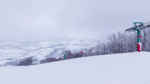 Sífelvonók a háttérben hófödte hegyek és egy hegyi gleccser. Üres egyszemélyes székek fel-le mozognak a felvonón. Síelők, snowboardosok és turisták jöttek a hétvégére a turizmusért — Stock videók