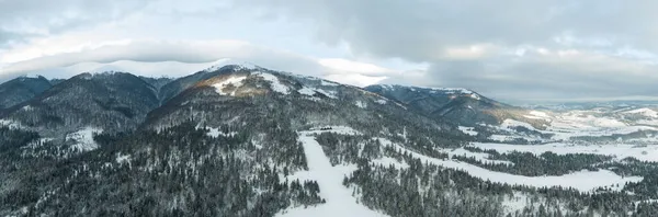 Vue aérienne du lever du soleil majestueux dans les montagnes. La vallée entre les montagnes est couverte de brouillard et est éclairée par les rayons chauds du soleil levant. Montagnes couvertes de forêt naturelle. — Photo