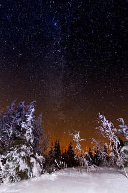 Kış dağları manzarası. Gökyüzünde yıldızlar olan gece manzarası. Geceleri dağların ve yıldızlarla dolu gökyüzünün muhteşem manzarası. Dağlarda güzel bir kış gecesi. Yüksek kalite fotoğraf