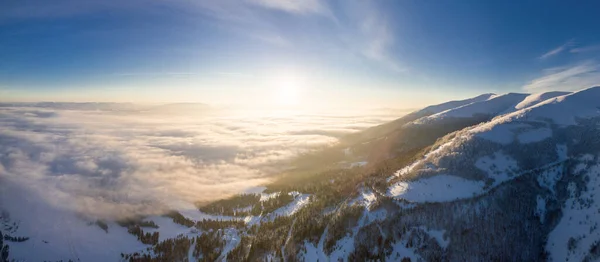 Luftaufnahme eines majestätischen Sonnenaufgangs in den Bergen. Tal zwischen den Bergen ist mit Nebel bedeckt und wird von den warmen Strahlen der aufgehenden Sonne beleuchtet. Berge mit natürlichem Wald bedeckt. — Stockfoto