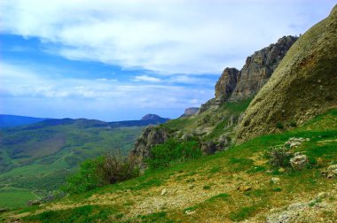 Kırım Yarımadası 'nın muhteşem manzarasına sahip yatay bir arka plan. Dağların üst manzarası yemyeşil ve tepenin altındaki kalın bulutlarla kaplıydı. Açık mavi gökyüzü. Boşluğu kopyala.