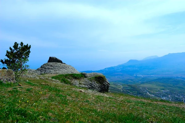 Sfondo orizzontale con un magnifico paesaggio della penisola di Crimea. Vista dall'alto delle montagne ricoperte di verde lussureggiante e le spesse nuvole sotto le cime. Cielo blu chiaro. Copia spazio. — Foto Stock