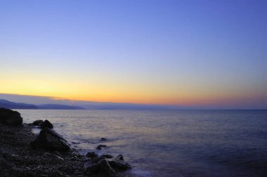 Karadeniz 'de gün batımı. Güzel bulutlar, mavi gökyüzü, ufukta güneş. Ön planda güzel taşlar