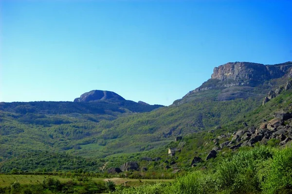 Horizontaler Hintergrund mit einer herrlichen Landschaft der Halbinsel Krim. Blick von oben auf die mit üppigem Grün bedeckten Berge und die dicken Wolken unterhalb der Gipfel. Strahlend blauer Himmel. Kopierraum. — Stockfoto