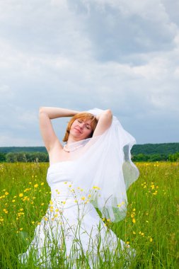 Düğün günü, güzellik, doğa konsepti. Tarlanın ortasında beyaz gelinlik giyen harika bir kadın var. Kendi etrafında dönüyor ve pullar güneşin ışığında parlıyor.