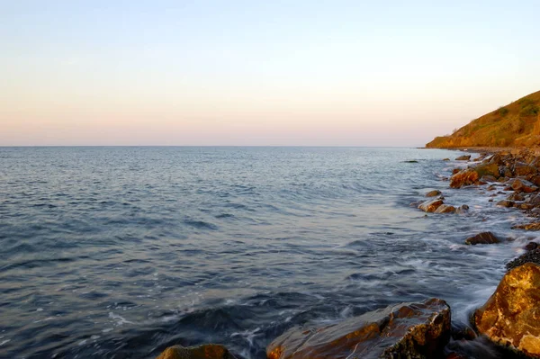 Tramonto sul Mar Nero. Belle nuvole, cielo blu, sole all'orizzonte. Belle pietre in primo piano — Foto Stock