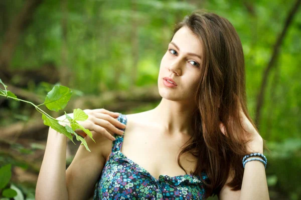 Hermosa joven vestida con elegante vestido blanco caminando por un sendero forestal con rayos de luz solar brillando a través de las hojas de los árboles —  Fotos de Stock