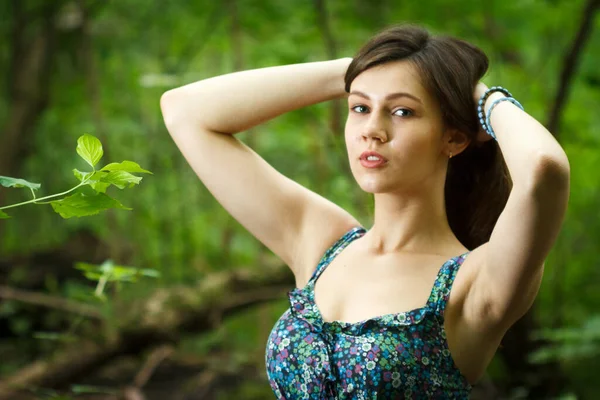 Mulher bonita vestindo vestido branco elegante andando em um caminho da floresta com raios de luz solar irradiando através das folhas das árvores — Fotografia de Stock