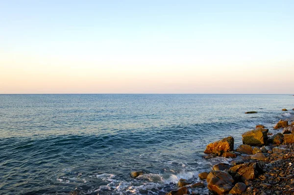 Tramonto sul Mar Nero. Belle nuvole, cielo blu, sole all'orizzonte. Belle pietre in primo piano — Foto Stock