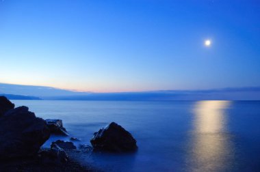 Karadeniz 'de gün batımı. Güzel bulutlar, mavi gökyüzü, ufukta güneş. Ön planda güzel taşlar