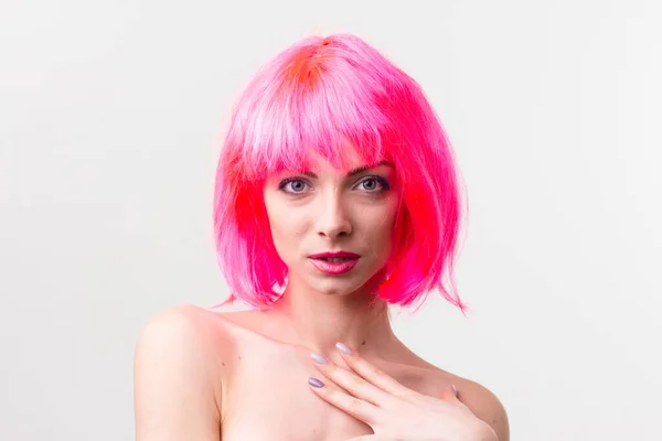 Imagen de la hermosa mujer excitada en la peluca riendo mientras posando con dulces aislados sobre fondo rosa — Foto de Stock