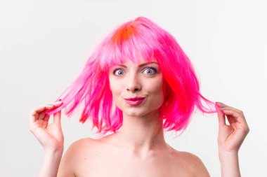 Pembe arka planda izole edilmiş şekerlerle poz veren peruklu güzel bir kadının görüntüsü