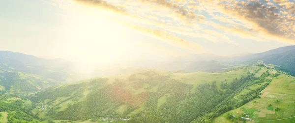 Vista aérea das pastagens exuberantes intermináveis das extensões dos Cárpatos e das terras agrícolas. Campo agrícola cultivado. Paisagem montanhosa rural ao pôr do sol. Ucrânia. — Fotografia de Stock