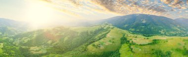 Karpatlar 'ın uçsuz bucaksız otlaklarının ve tarım arazilerinin havadan görünüşü. Tarım tarlası. Gün batımında kırsal dağ manzarası. Ukrayna.