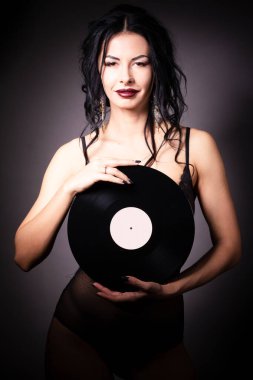 Çekici bir kızın vinil plakla çekilmiş bir fotoğrafı ve pembe bir arka plana bakıyor..