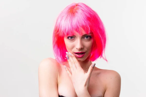 Изображение возбужденной красивой женщины в парике смеясь во время позирования с конфеты изолированы на розовом фоне — стоковое фото