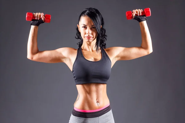 Женщина с мускулистым телом готова носить перчатки для тренировок на сером фоне — стоковое фото