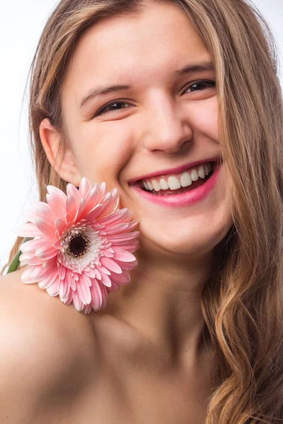 Beyaz zemin üzerinde bir göz üzerinden bir çiçek tutarak taze cilt ile mutlu bir kız portresi. Beyaz tişörtü giyen güzel kızıl saçlı kıvırcık kadın pnik çiçek portresi kapatın. Güzellik ve Bahar