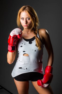 Spor giyimli, kaslı, genç sporcu bir kadın. Spor salonunda siyah bir arka planda bando ya da eldiven takıyor. Spor dövüş sanatları. Spor malzemesi ve spor malzemesi reklamları için yer kopyala. 