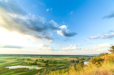 Nehiri olan güzel bir vadi, büyük bulutları ve parlak güneşi olan mavi bir gökyüzü. Hava 4K UHD