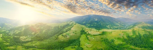 Vista aérea das pastagens exuberantes intermináveis das extensões dos Cárpatos e das terras agrícolas. Campo agrícola cultivado. Paisagem montanhosa rural ao pôr do sol. Ucrânia. — Fotografia de Stock