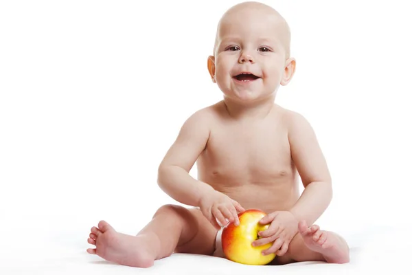 Szczęśliwy dziecko chłopiec siedzi w pieluchy i jedzenie czerwone żółte jabłko niebieskie oczy patrząc na rogu izolowane na białym tle — Zdjęcie stockowe