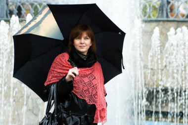 Şık, çekici, genç bir kadın sonbahar kıyafetiyle caddede yürüyor, kırmızı örgü eşarp, mutlu ruh hali, moda tarzı..