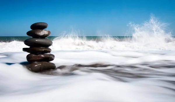 Underbar natur Glänsande och polerade stenar staplade på stranden med många polerade stenar på Krimhalvön. Bakgrunden är havet, en stenstrand med några andra öar. — Stockfoto