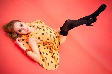 Memnun olmayan kadın pembe arka planda çapraz kollarla poz veriyor.