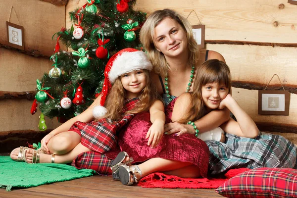 La madre insieme nella piccola figlia, si sieda su un piano vicino a un abete festivo, giochi e consideri regali. In attesa di una vacanza — Foto Stock