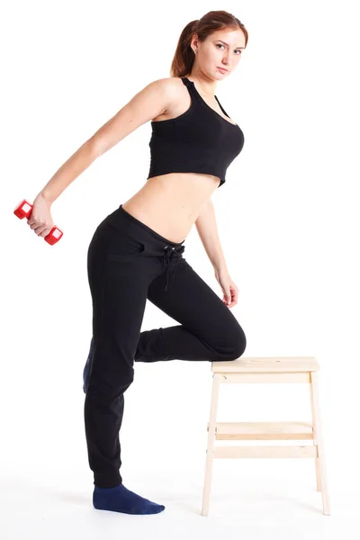 Modelo de fitness feminino excercising em estúdio com pesos dunbell e fazendo uma rotina de chão de trechos e elevadores em um fosco . — Fotografia de Stock