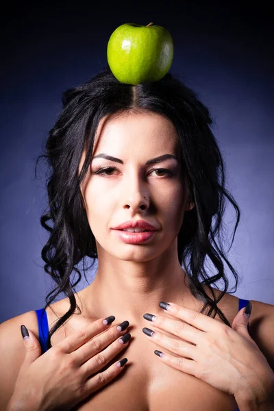 Απόκριες. Μια τρομερή κακιά μάγισσα κρατά ένα δηλητηριασμένο μήλο στα χέρια της, στέκεται στη φωλιά της ανάμεσα στους ιστούς αράχνης. Σατανική μαύρη μαγεία. Φωτογραφία Αρχείου