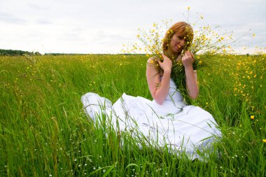 Düğün günü, güzellik, doğa konsepti. Tarlanın ortasında beyaz gelinlik giyen harika bir kadın var. Kendi etrafında dönüyor ve pullar güneşin ışığında parlıyor.