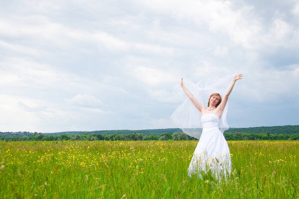 wedding day, beauty, nature concept. in the middle of the field there is an amazing woman wearing white bride dress, she is spinning around herself and sequins are shining in the light of sun