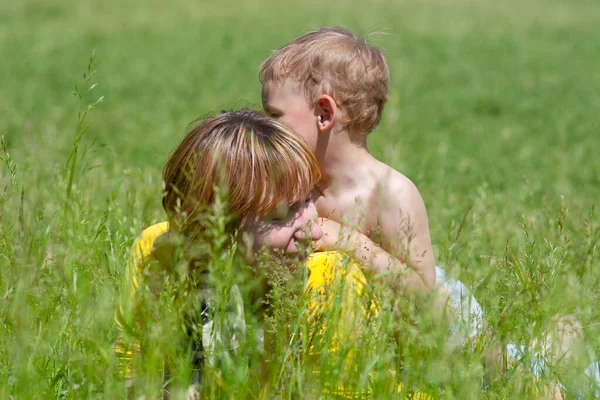 Jovem mãe e sua filha de um ano de idade descansando no parque na grama. Família se divertindo juntos. — Fotografia de Stock