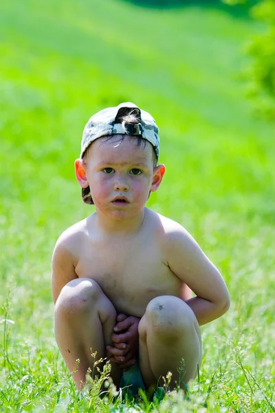 Çimlerin üzerinde oturan çocuk