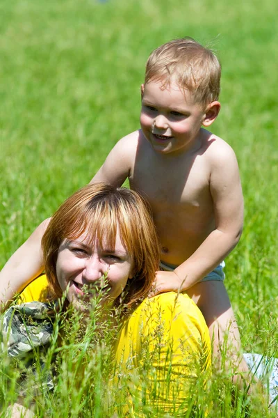 Genç anne ve bir yaşındaki kızı parkta çimlerin üzerinde dinleniyorlar. Aile birlikte eğleniyor.. 