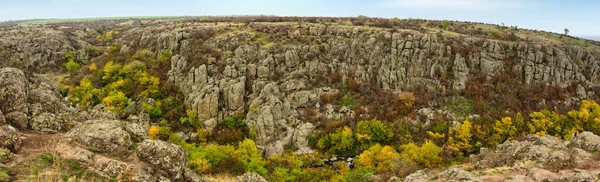 Велика кількість кам'яних мінералів, покритих зеленою рослинністю, лежить над невеликою річкою в мальовничій Україні та її гарній природі. — стокове фото