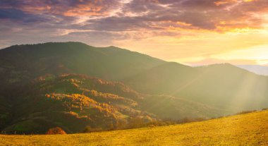 Ukraine. Warm autumn in a village. Picturesque beech, birch and pine forests and Hutsul houses against the backdrop of the Synevyr Pass ridge are very beautiful with bright colors after a fine day.